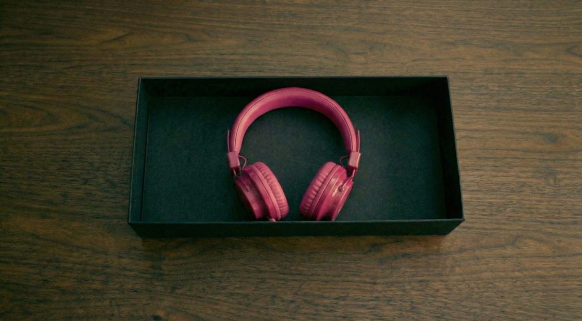A pair of pink headphones in an open black box on a wooden desk