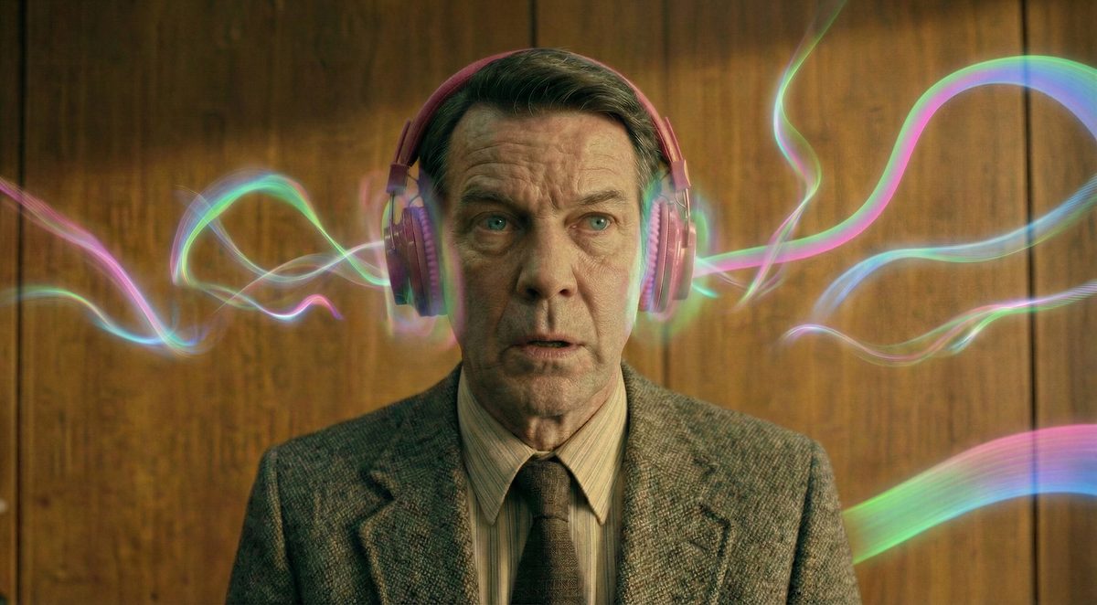 The CEO wearing pink headphones, as ribbons of coloured signal flow in towards him